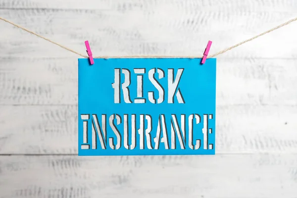 Handwriting text Risk Insurance. Concept meaning The possibility of Loss Damage against the liability coverage Clothesline clothespin rectangle shaped paper reminder white wood desk.