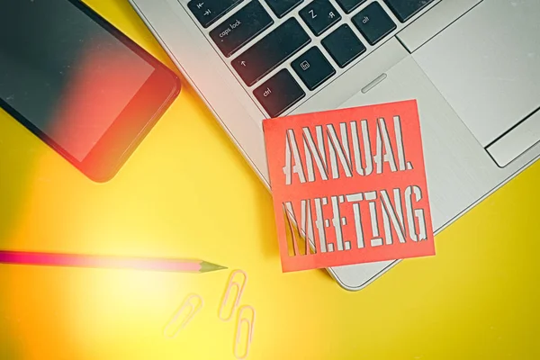 Text sign showing Annual Meeting. Conceptual photo Yearly gathering of an organization interested shareholders Trendy laptop smartphone blank sticky note pencil clips colored background.
