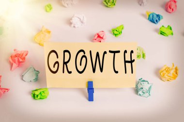 Büyüdüğünü gösteren kavramsal el yazısı. İş fotoğrafı gösterme süreci boyut ve meyve suyu artışı Yaşlanan Renkli buruşmuş kağıt boş hatırlatıcı beyaz zemin çamaşır mandalı.