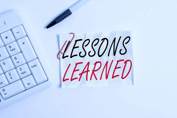 Szövegírási szöveg Lessons Learned. Üzleti koncepció a tapasztalatok desztillált projekt, amely aktívan kell venni White pc billentyűzet üres jegyzet papír felett fehér háttér. — Stock Fotó
