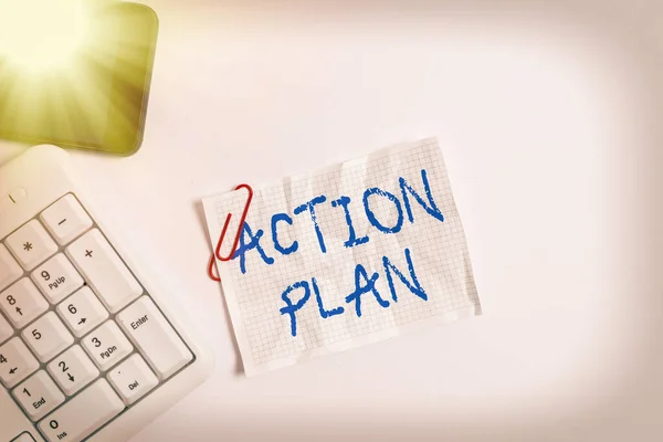 Handwriting text Action Plan. Concept meaning proposed strategy or course of actions for certain time White pc keyboard with empty note paper above white background and mobile phone.