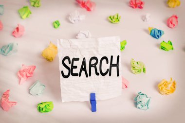 Arama 'yı gösteren not yazılıyor. İş fotoğrafı gösterimi dikkatlice renkli buruşmuş kağıt arayarak bir şey bulmaya çalışın. Boş hatırlatıcı beyaz zemin çamaşır mandalı.