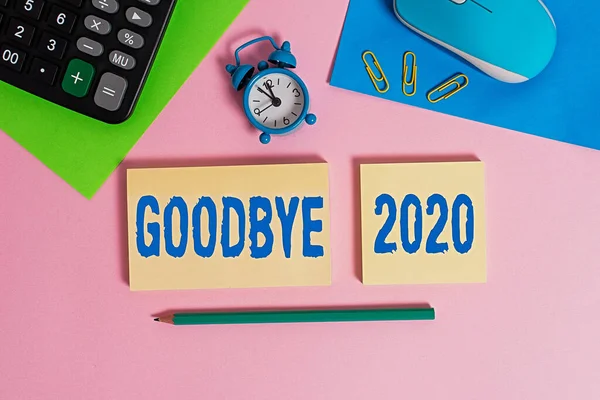 Handwriting text Good Bye 2020. Concept meaning express good wishes when parting or at the end of last year Wire mouse clock calculator notepads marker sheets clips color background.