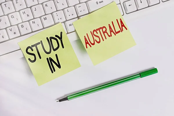 Schrijfbriefje met Studie in Australië. Zakelijke foto presentatie gaan in het buitenland orde voltooien van uw studies Vierkante groene notitie papier met potlood op de witte achtergrond. — Stockfoto
