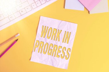 Kelime yazma çalışmaları devam ediyor. Tamamlanmamış proje için iş konsepti, masadaki pc klavyesiyle sarı arkaplan üzerindeki dizüstü bilgisayara hala eklenen ya da geliştirilen kopya alanı.