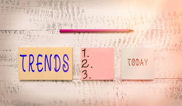 Escribir texto a mano Tendencias. Concepto que significa dirección general en la que algo se está desarrollando o cambiando Tres bloc de notas en blanco multicolor rotulador lápiz madera vintage fondo . — Foto de Stock