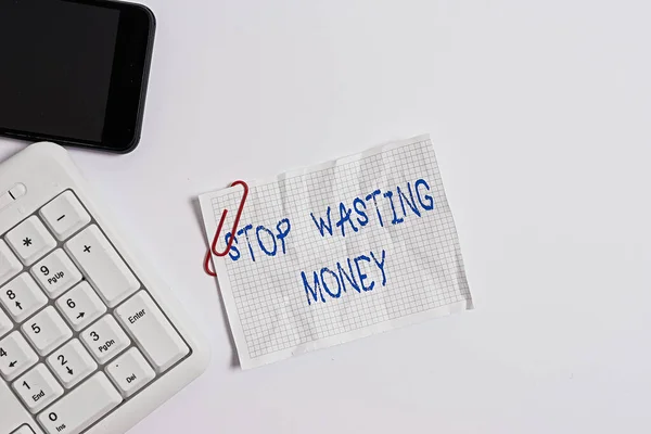 Handwriting text Stop Wasting Money. Concept meaning advicing an individual or group to start saving and use it wisely White pc keyboard with empty note paper above white background and mobile phone.