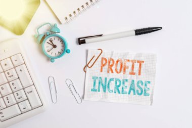 Profit Increase 'i gösteren kavramsal el yazısı. İş fotoğrafı metni, bir şirketten elde edilen gelir miktarı bilgisayar cep telefonlu saat kalemi ve kağıt üzerinde düz yatıyordu.