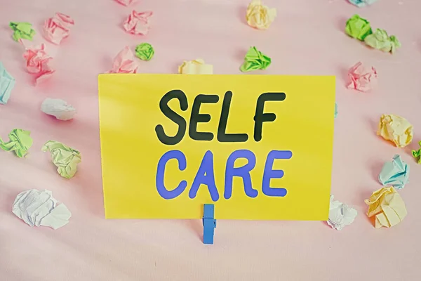 Text sign showing Self Care. Conceptual photo the practice of taking action to improve one s is own health Colored crumpled papers empty reminder pink floor background clothespin. — Stock Photo, Image