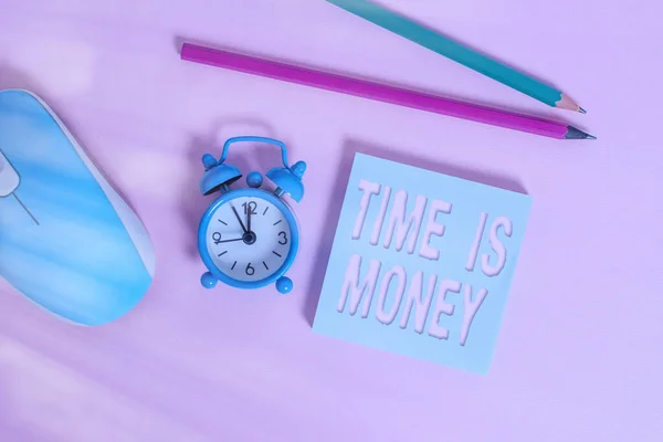 Text sign showing Time Is Money. Conceptual photo time is a valuable resource Do things as quickly as possible Alarm clock wakeup blank notepad mouse markers colored background.
