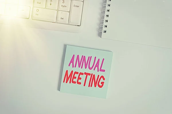 Handwriting text writing Annual Meeting. Concept meaning yearly meeting of the general membership of an organization Empty note paper on the white background by the pc keyboard with copy space.