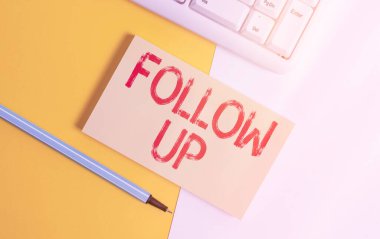 Follow Up 'ı gösteren kavramsal el yazısı. İş fotoğrafı metni, daha önce başlatılmış bir şeyin devamıdır. Fotokopi alanı ve klavyesi turuncu arkaplan tablosunun üzerinde olan kağıt.