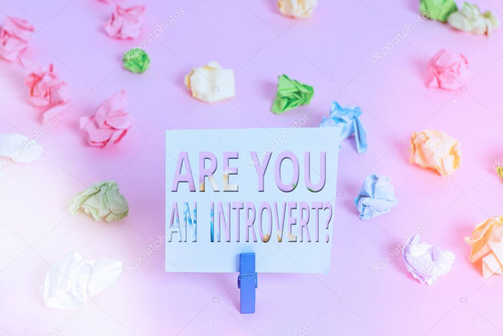 Word writing text Are You An Introvertquestion. Business concept for an individual who tends to turn inward mentally Colored crumpled papers empty reminder pink floor background clothespin.