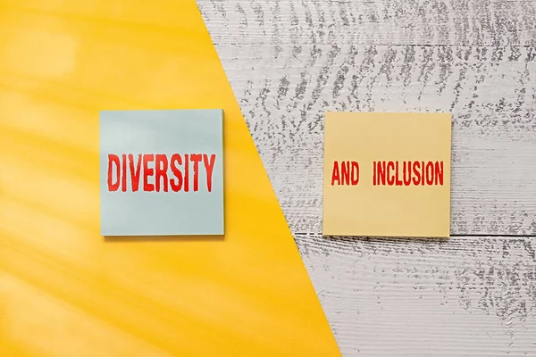 Text sign showing Diversity And Inclusion. Conceptual photo range difference includes race ethnicity gender Two multicolor blank notepads colored paper sheet retro wooden background.