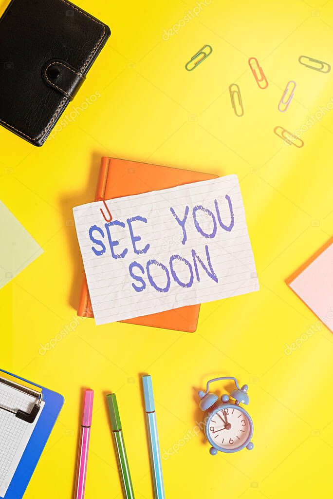 Writing note showing See You Soon. Business concept for used for saying goodbye to someone and going to meet again soon Flat lay above empty paper with pencils and paper clips