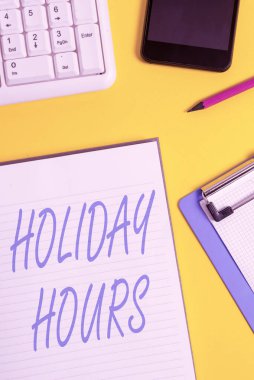 Holiday Hours 'u gösteren kavramsal el yazısı. İş fotoğrafçıları her saat için normal ücretlerinin iki katını alıyor. Masa saati ve bilgisayar klavyesinde buruşmuş beyaz kağıt..