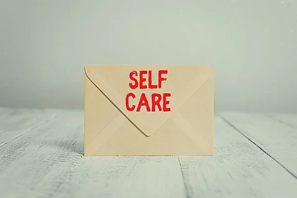 Handwriting text writing Self Care. Concept meaning the practice of taking action to improve one s is own health Closed standing rectangular colored envelope old wooden vintage background. — Stock Photo, Image