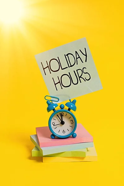 El yazısı, Holiday Hours. Konsept, çalışanın her saat için normal maaşının iki katını alacağı anlamına gelir. Metal alarm saati boş yapışkan not defterleri renkli arka plan. — Stok fotoğraf