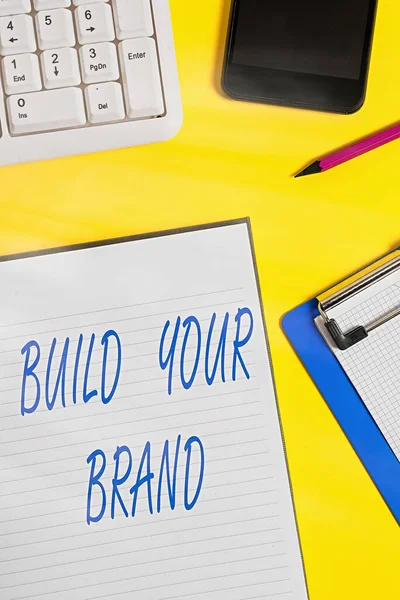 Conceptual hand writing showing Build Your Brand. Business photo showcasing enhancing brand equity using advertising campaigns Crumpled white paper on table clock mobile and pc keyboard. — Stock Photo, Image