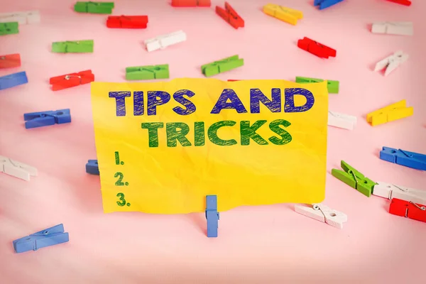 Handwriting text writing Tips And Tricks. Concept meaning piece of inside facts specially in betting or investing Colored clothespin papers empty reminder pink floor background office pin.