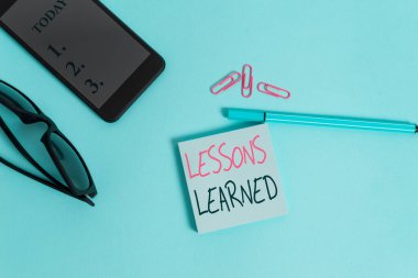 Kelime yazma dersleri alındı. Tecrübe ile kazanılan bilgi veya anlayış için iş konsepti gözlük renkli yapışkan not akıllı cep telefonu klipleri kalem pastel arka plan.
