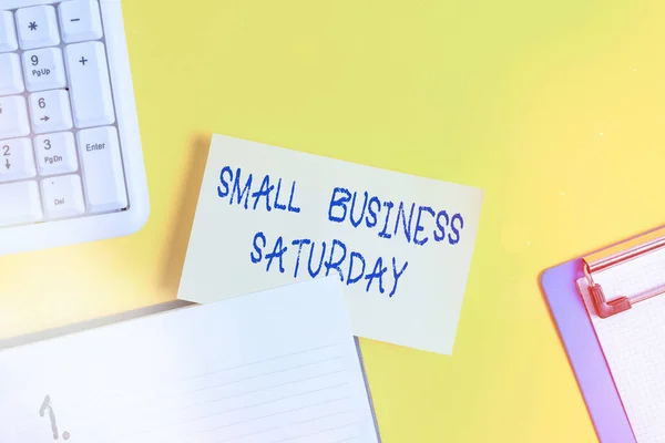 Escrevendo uma nota mostrando Small Business Saturday. Foto de negócios mostrando feriado americano de compras realizadas durante o sábado Papel laranja vazio com espaço de cópia na mesa amarela . — Fotografia de Stock