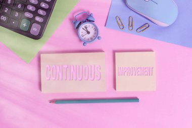 El yazısı metni sürekli geliştirme. Ürün veya süreçleri geliştirmek için devam eden çaba anlamına gelen kavram Fare saat hesap makinesi not defterleri renk arkaplanını kırpar.