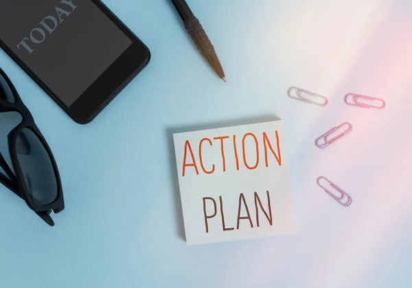 Text sign showing Action Plan. Conceptual photo detailed plan outlining actions needed to reach goals or vision Eyeglasses colored sticky note smartphone cell clips pen pastel background.