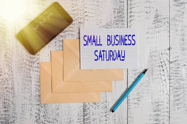 Conceptual hand writing showing Small Business Saturday. Business photo showcasing American shopping holiday held during the Saturday Envelopes marker ruled paper smartphone wooden background. clipart