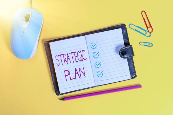 Writing note showing Strategic Plan. Business photo showcasing a systematic process of envisioning a desired future Leather locked diary striped sheets marker mouse colored background.