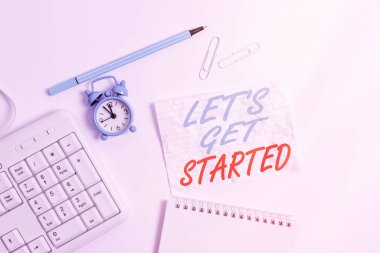 Kelime yazma metni Başlayalım. Başlattığınız bir şey üzerinde çalışma ya da yapmaya başlama konsepti Masada saat ve kalem olan boş not kağıdına boşluk kopyala.