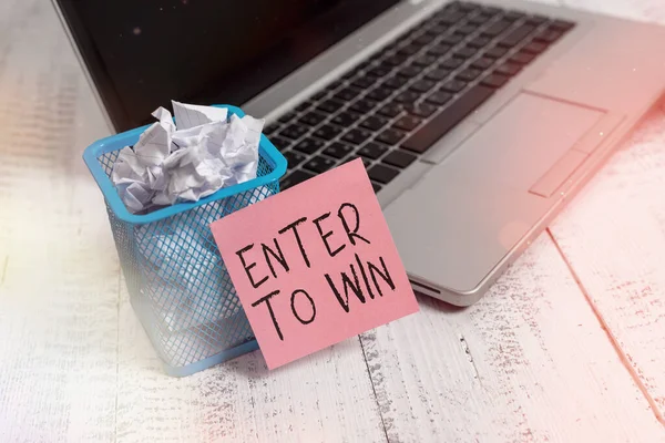 Text sign showing Enter To Win. Conceptual photo exchanging something value for prize or chance of winning Metallic laptop sticky note pad waste basket crushed paper vintage table.