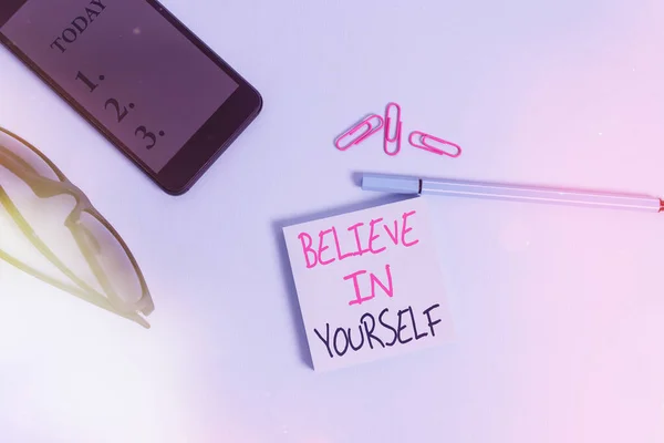 Word writing text Believe In Yourself. Business concept for common piece of advice that you can do everything Eyeglasses colored sticky note smartphone cell clips pen pastel background. — Stock Photo, Image