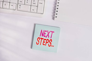 Sonraki Adımlar 'ı yazan el yazısı. Anlamı, başka bir şeyi bitirdikten sonra yaptığınız ya da planladığınız bir şey. Pc klavyesinin yanındaki beyaz arkaplan üzerine boş not kağıdı kopyalama alanı ile birlikte..