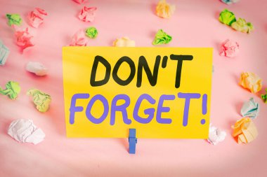 Mesaj işareti Don 't Forget' u gösteriyor. Birine önemli bir gerçeği veya detayı hatırlatmak için kullanılan kavramsal fotoğraf. Renkli buruşuk kağıtlar boş hatırlatıcı pembe zemin çamaşır mandalı..