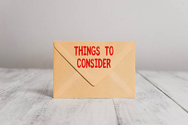 Handwriting text writing Things To Consider. Concept meaning think about carefully especially in making decisions Closed standing rectangular colored envelope old wooden vintage background.