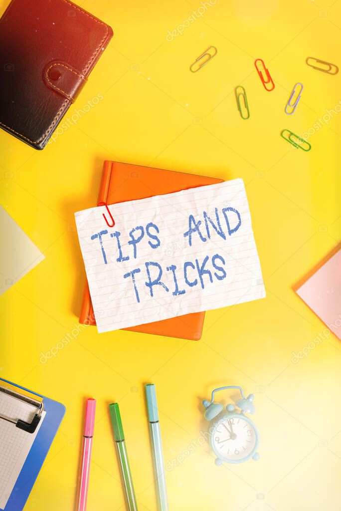 Writing note showing Tips And Tricks. Business photo showcasing piece of inside facts specially in betting or investing Flat lay above empty paper with pencils and paper clips.