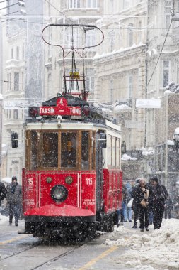 Tramvay ve Istiklal Caddesi'ndeki kar yağmur altında günlük yaşamda insan
