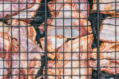 Pişirme işleminin başında ızgarada ızgara domuz pirzolası. Üst yakın çekim görüntüsü. Parlak yaz güneşinin altında.
