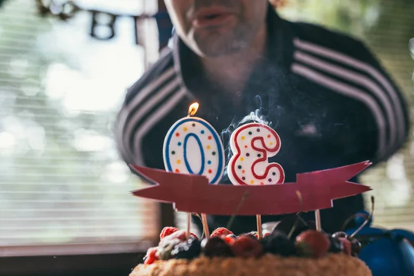 Aniversariante apaga as velas em forma de 30 em framboesas bolo de aniversário de amora. tiro macro foco seletivo com DOF rasa — Fotografia de Stock