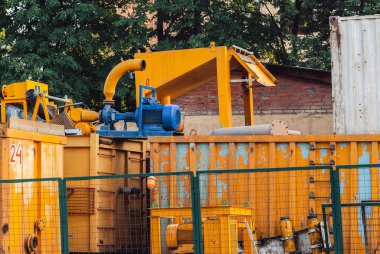 Modern endüstriyel ekipmanlar ve yeşil çitin arkasındaki sarı kaplar için mavi ile boyanmış güçlü elektrikli motorlar.