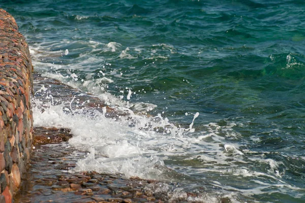 Фото красивої чистої бірюзової поверхні морської води з бризами і яскравими бризками на кам'яному морському фоні, горизонтальна картина — стокове фото