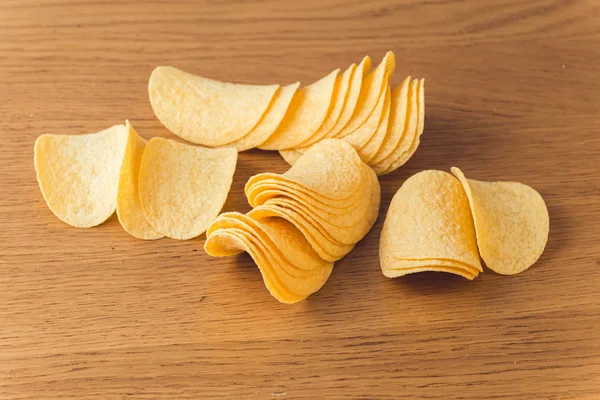 Delicious potato chips, laying on wooden table background — Stock Photo, Image