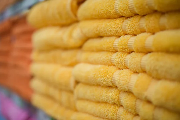 Una pila de toallas naranjas y amarillas en la tienda. Tiro macro de enfoque selectivo borroso extremo con DOF poco profundo —  Fotos de Stock