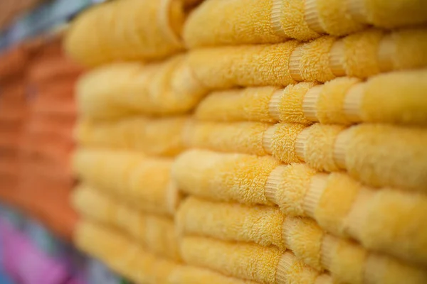 En hög med orange och gula handdukar i butiken. Extremt suddig selektiv fokus makro skott med grund Dof — Stockfoto