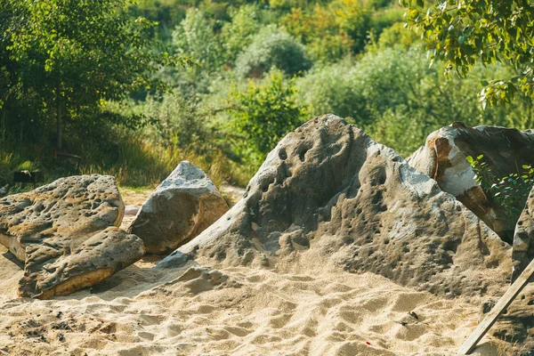 巨大的、古老的鹅卵石躺在长满青草和灌木的山上的沙滩上。春阳天。浅层Dof选择性聚焦宏投篮 — 图库照片