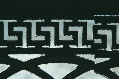 Eski, siyah, dökme demir bir çitin Yunan tarzında bir parçası. Zamandan ve yüksek sıcaklıklardan gelen boya eriyik damlalar oluşturur.