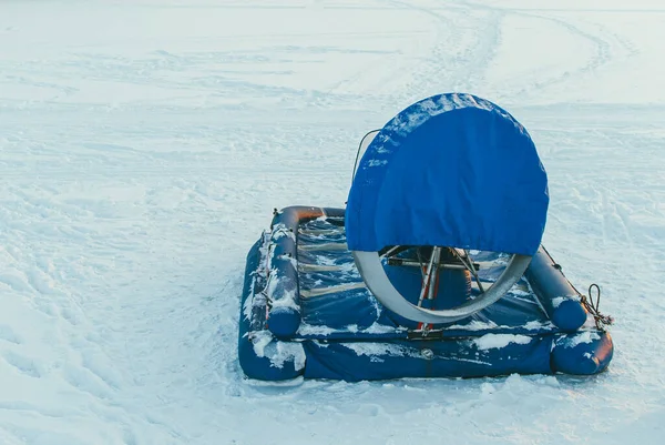 Un aerodeslizador de transporte en cubiertas protectoras azules se encuentra en un lago congelado lleno de nieve y hielo. Copyspace para su texto y diseño — Foto de Stock