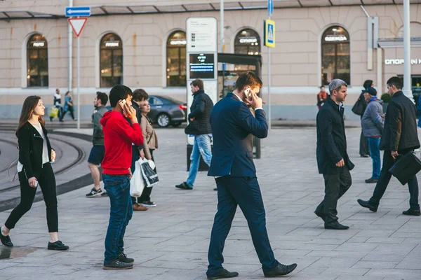 Moskova, Rusya - 25 Mayıs 2017. Farklı cinsiyetlerden ve yaşlardan oluşan bir kalabalık yaya geçidinde cadde boyunca ilerliyor. Ön planda iki adam telefonda konuşuyorlar.