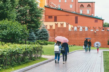 Moskova, Rusya - 7 Temmuz 2017. Birkaç grup insan Moskova 'da Kremlin yakınlarında bir cadde boyunca yürürler. Yağmur yağarken şemsiye tutuyorlar.